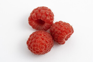 Three ripe raspberries isolated on a white background close-up. Fresh raspberries without sheets on the table. Macro shooting. Healthy and wholesome food concept