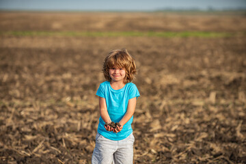 Naklejka na ściany i meble Kids farmer. American child on farm. Soil and ground concept. Textured fertile soil as background. Gardening season.
