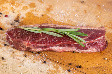 Raw beef steak on a dark wooden table.