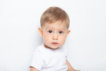 Naklejka premium Caucasian brown-eyed baby boy in a white T-shirt on a white background