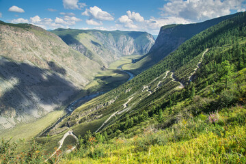 Naklejka premium A dangerous road descends into a deep gorge. Mountain pass. Travel and summer vacation.