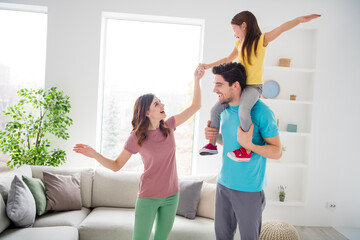 Fototapeta na wymiar Photo of positive cheerful three people mommy daddy carry shoulders little kid girl hold hand in house indoors