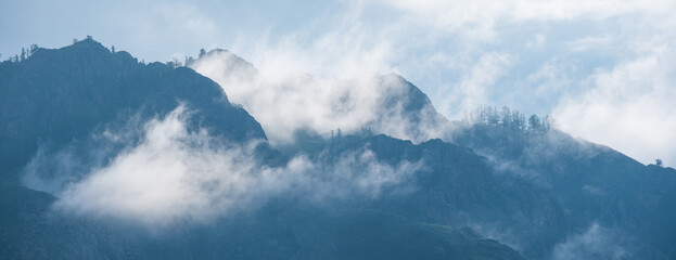 Mountain peaks in the clouds. Panoramic view.