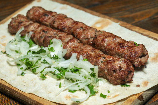 lula kebab with herbs on a wooden surface