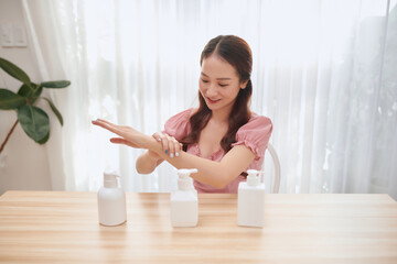 Beautiful Asian woman using hand sanitizer at home.