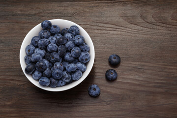 Blueberries in a saucer on a varnished wooden table. Dark blue, juicy and large blueberries.