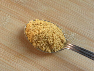 Yellow color Sugarcane jaggery powder on stainless steel spoon