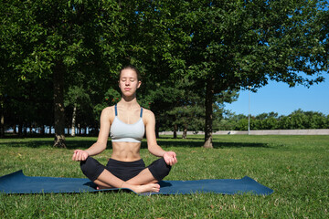 Young slim girl doing yoga, lotus position, relaxation and meditation