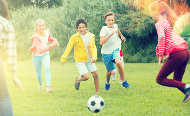 Happy children are jogning and playing football in the park.