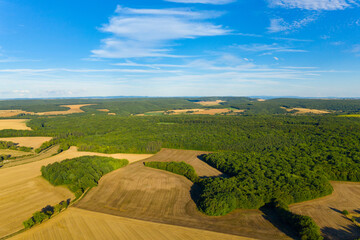Cette photo a été prise vers Nevers, dans la Nièvre, en Bourgogne, en France, en été, en drone. Elle montre des champs de blé et ses bottes de paille après la moisson et des forêts en arrière plan.