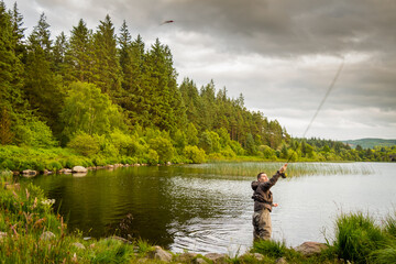 An action shot of a fly fisherman casting a pike fly on Loch Stroan, Scotland