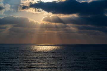 Beautiful sunset with blue sky and golden colors sun beams light over the sea ocean with dramatic clouds in the sky concept of romantic time on vacation