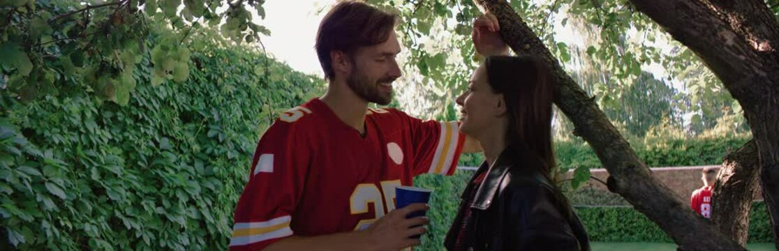 Young couple flirting and kissing under the tree during college party. Spring break, college life. Shot on RED cinema camera with 2x Anamorphic lens