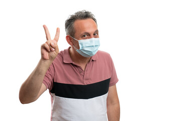 Hopeful man wearing medical mask and showing peace gesture