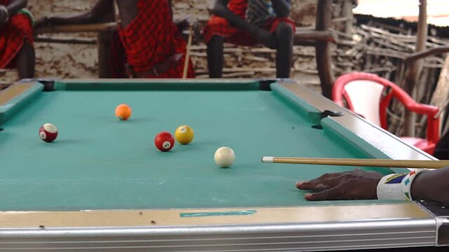 African masai men playing open air billiard pool in the village Engare Sero at Masailand