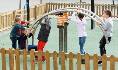 Smiling children playing on swing at playground at street