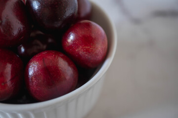 Close up on a red bowl of cherries.  Food photo with monochromatic red colour palette and plain background with space for copy text