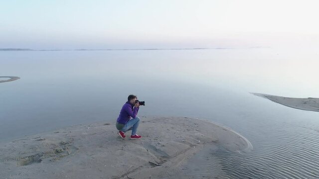 Woman photographer by the lake takes pictures of the morning lake in the fog. Departure by drone.