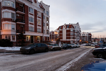 Empty city street, parked cars and road in snow.