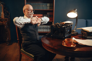 Elderly writer prepares to work on typewriter