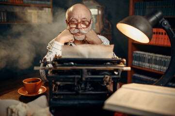 Elderly writer thinks at vintage typewriter