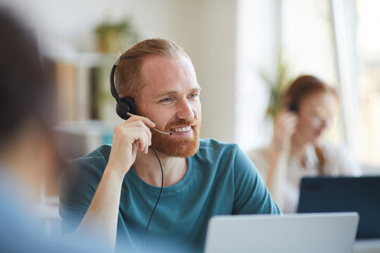 Mature Bearded Man In Headphones Working At The Table With Laptop At Office