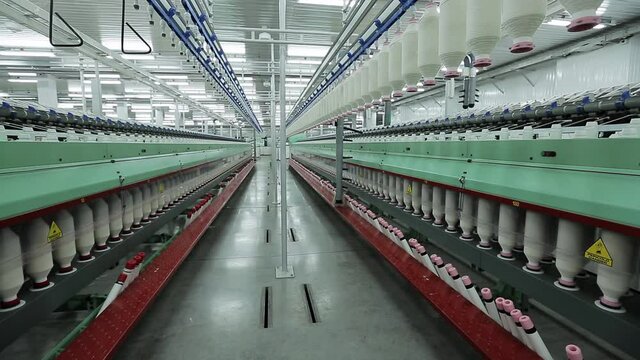Workshop of a textile factory, machines produce threads from cotton fiber. Textile industry.