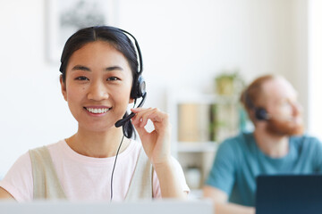 Portrait of happy smiling female customer support phone operator at workplace
