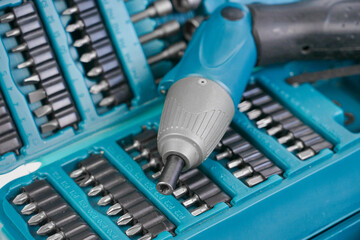 Electric screwdriver lies next to the drawer with a set of screwdrivers