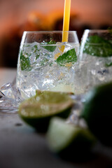 two refreshing cocktails with green ingredients in glass jugs standing on white wooden background