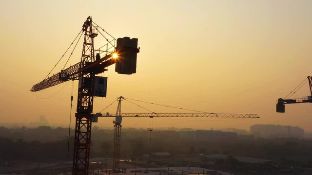 Aerial view from drone of construction site with cranes on sunrise sky background. Steel frame structure, structural steel beam build large buildings at construction site . construction machinery.