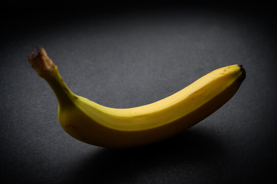 Ripe and natural looking banana on dark background. Selective focus.