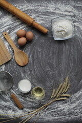 Fototapeta na wymiar Egg, flour, olive oil, milk, wheat ears, kitchen tool on gray table background.