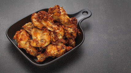 fried chicken with black pan on the dark tone texture background