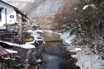 Fototapeta premium Japanese Onsen next to river in snowy forest, Nikko