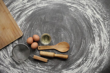 Chicken egg, flour, olive oil, kitchen tool on gray table background. Products