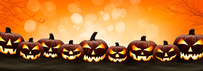 Nine halloween, Jack O Lanterns, with evil spooky eyes and faces isolated against a orange and yellow bokeh sky background.