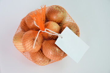 Onions in net bag with white tag isolated on gray