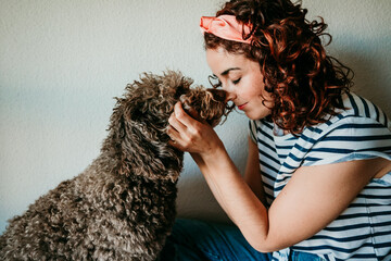 .Smiling young woman petting and playing with her adorable brown dog. With her pet she does not feel alone. Lifestyle