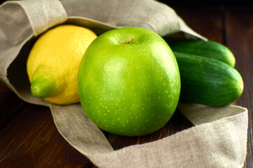 Green apple, lemon and cucumbers in reusable textile shopping bag