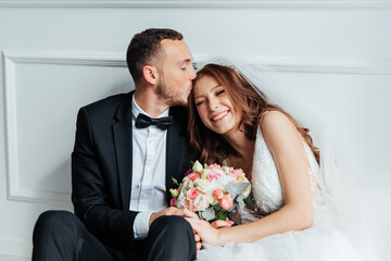 The first meeting of the groom in a black suit and the bride in a white wedding dress with a bouquet in the interior of a photo studio on a white and black background