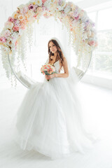 Fototapeta premium The first meeting of the groom in a black suit and the bride in a white wedding dress with a bouquet in the interior of a photo studio on a white and black background