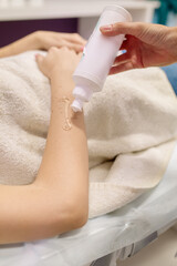 The doctor applies a protective gel to the patient's hand before the laser hair removal procedure in the beauty salon