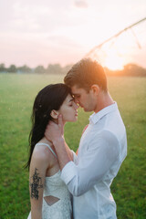 Couple in love embraces on lawn under water drops at sunset.