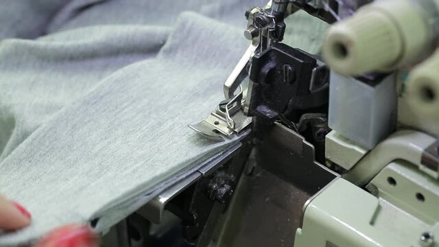 A woman processes fabric on an overlock sewing machine .Textile industry.Sewing fabrics.