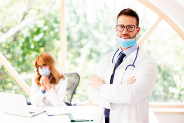 Male doctor wearing face mask while standing in doctor's room