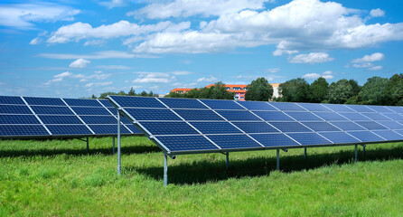 Solar power plant, blue solar panels on grass field under blue sky with clouds