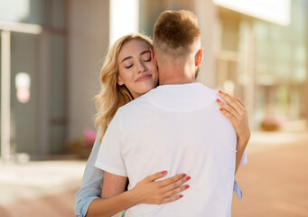 Affectionate couple cuddling, walking down the streets