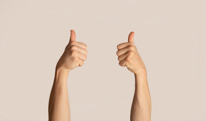 Unrecognizable man showing thumbs up gesture, expressing approval over light background