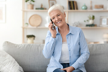 Communication Concept. Smiling elderly woman talking on mobile phone at home